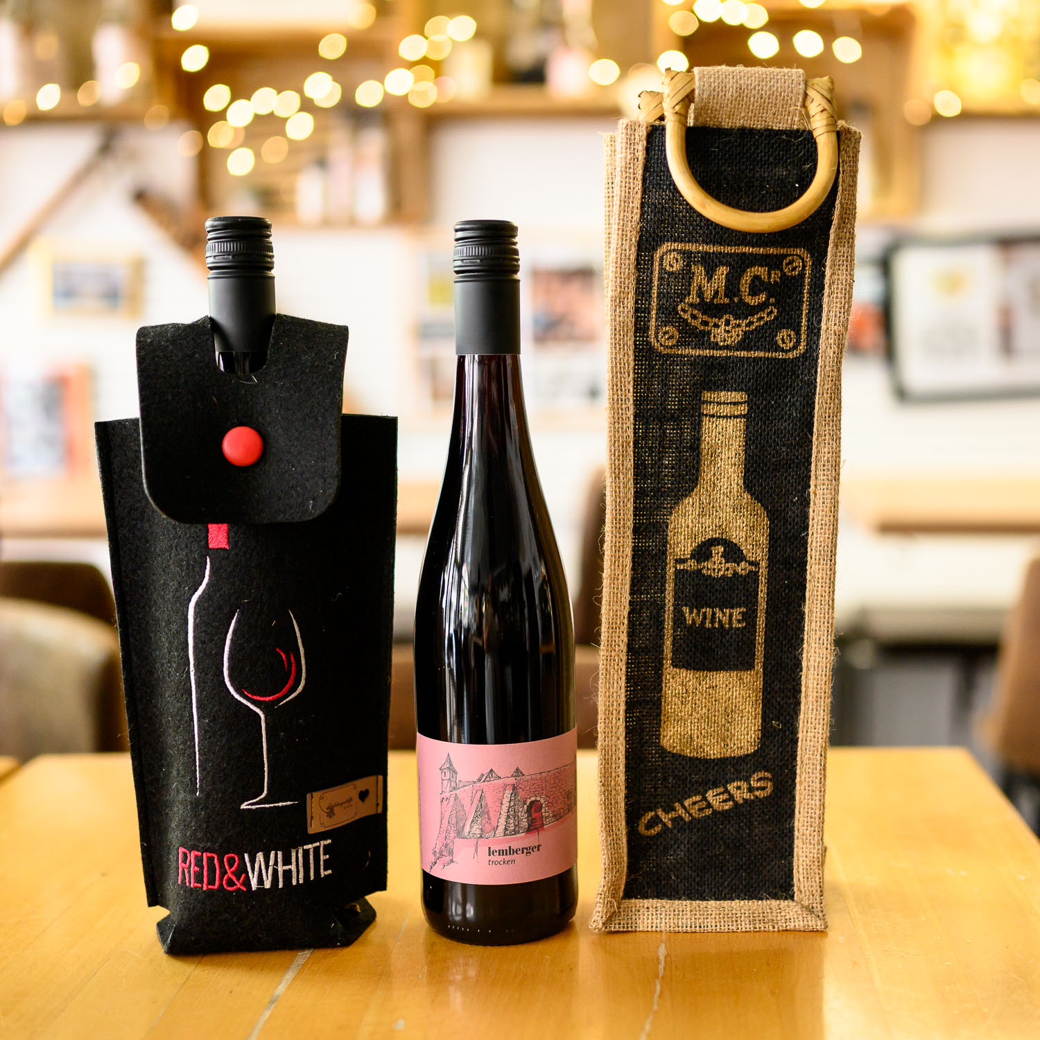 Geschenkverpackungen für eine Flasche Wein aus Filz und Jute stehen auf einem Tisch im Vinosseum